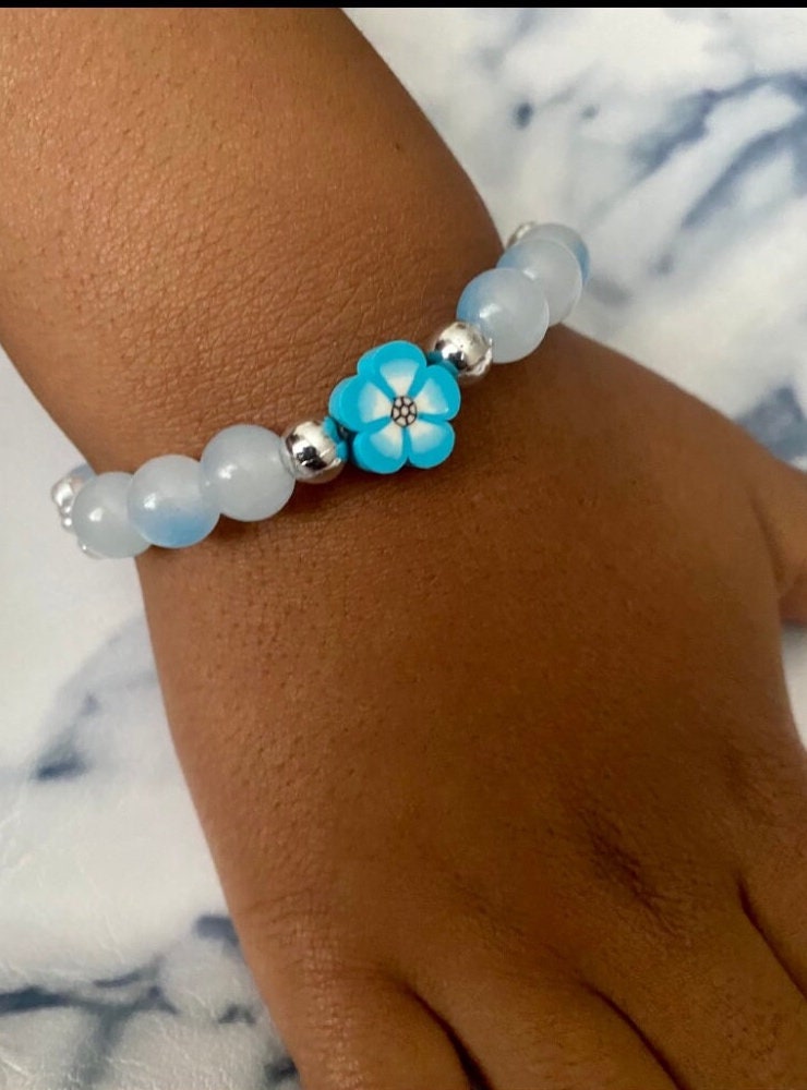 Small wrist beaded stretch bracelets tailored towards toddlers and little girls that come in colors purple and blue with a floral focus bead.