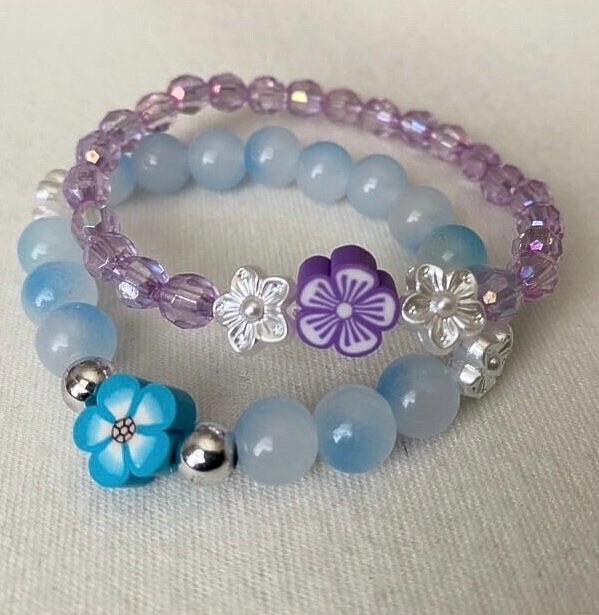 Small wrist beaded stretch bracelets tailored towards toddlers and little girls that come in colors purple and blue with a floral focus bead.