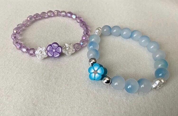 Small wrist beaded stretch bracelets tailored towards toddlers and little girls that come in colors purple and blue with a floral focus bead.