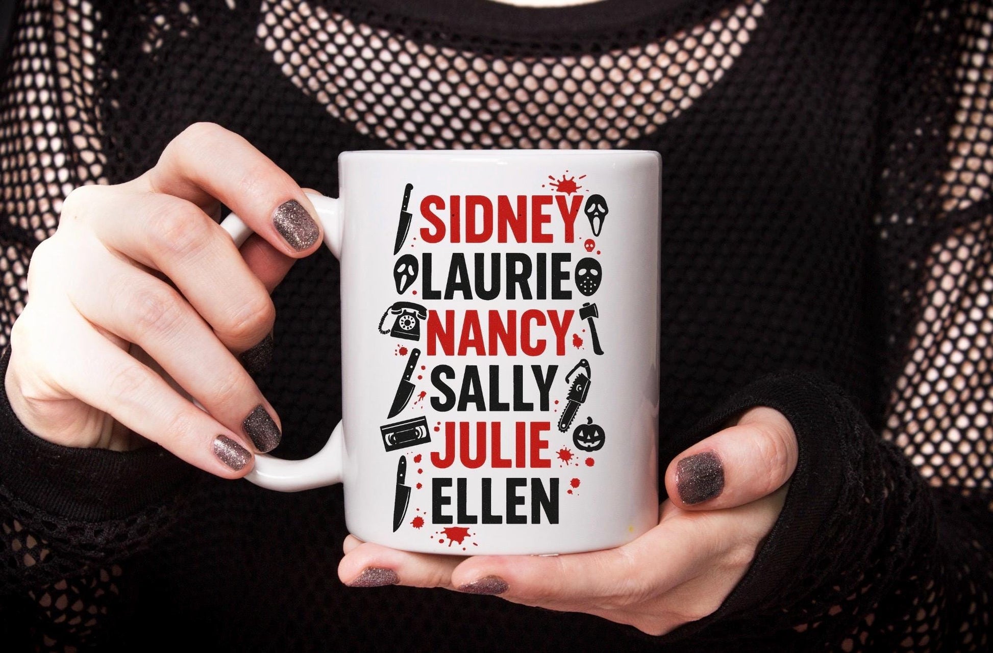 Close-up of hands holding horror-themed Final Girls mug. Woman holding the mug is dressed in a dark and goth aesthetic.